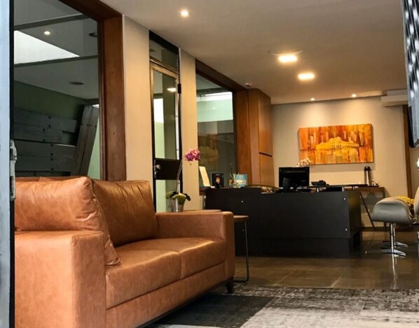 A modern lobby with a leather sofa, a reception desk, and a large abstract painting on the wall.