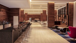 Eine moderne Bar mit einer langen Theke, mehreren Barhocker und einer Sitzecke mit Tischen und Stühlen.