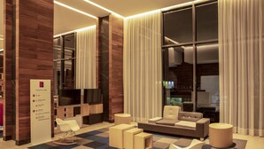 Eine moderne Hotelhalle mit Rezeption, Sitzgelegenheiten und großen Fenstern.