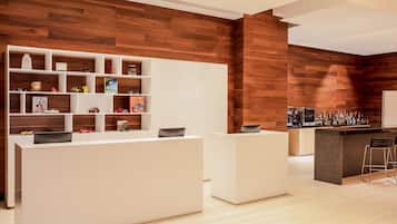 Una cocina moderna con detalles de madera, una zona de bar y un estante blanco con varios objetos.