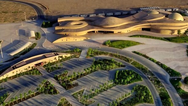 A modern building with a unique curved architecture, surrounded by landscaped areas and a desert landscape. - Sun Spring Hotel Dunhuang (Dunhuang)