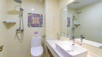 A modern bathroom with a white toilet, a large sink, and a shower with a handheld showerhead.