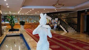 A lobby with a white statue, a reception desk, a staircase, and a red carpet. - Sun Spring Hotel Dunhuang (Dunhuang)