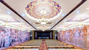 A conference room with a patterned ceiling, chandeliers, and a stage at the front. - Sun Spring Hotel Dunhuang (Dunhuang)