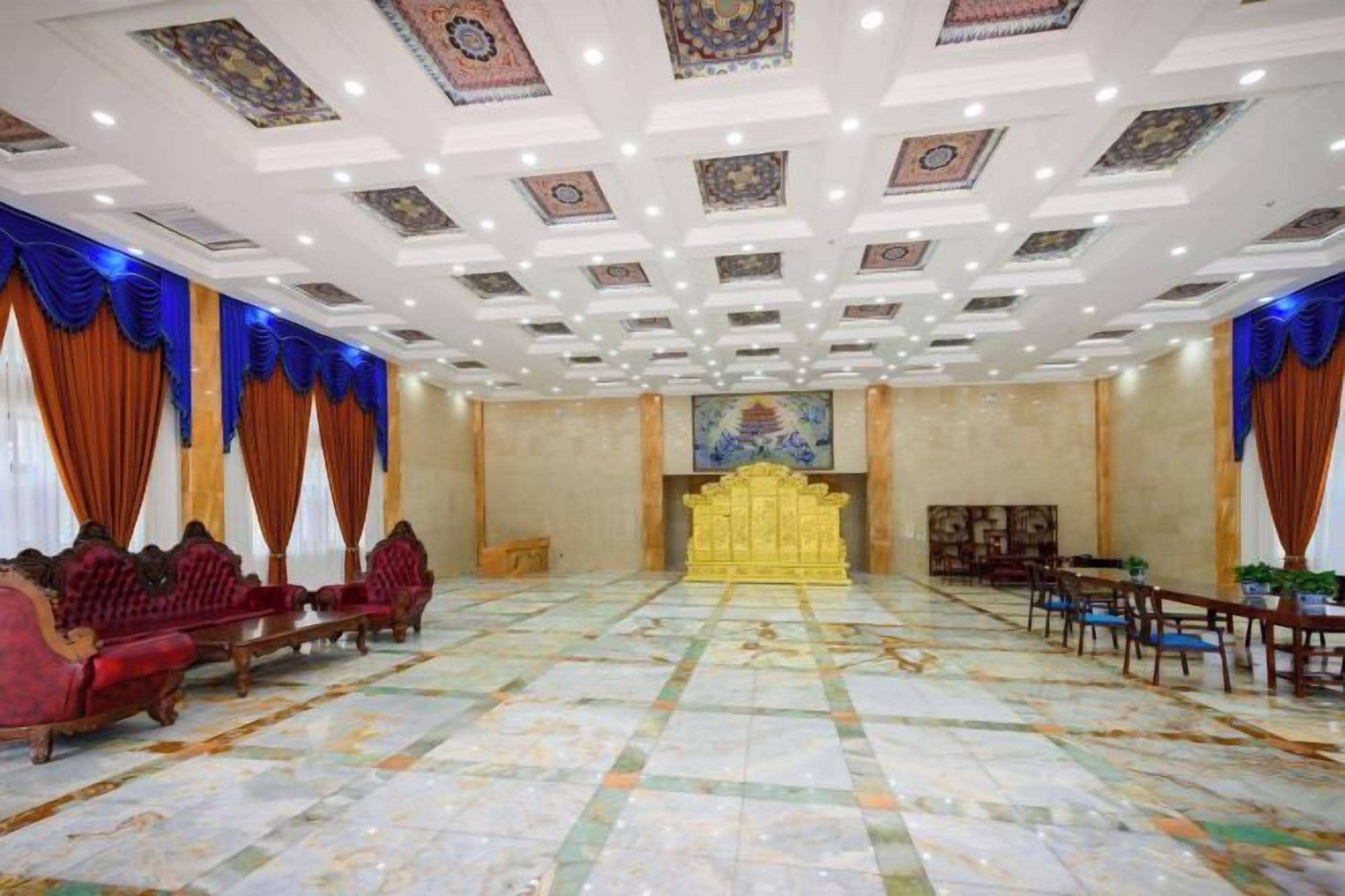 A large room with a patterned floor, a golden throne-like chair, and red upholstered chairs.