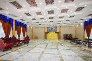 A large room with a patterned floor, a golden throne-like chair, and red upholstered chairs.