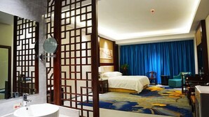 A hotel room with a large bed, a bathroom with a sink and mirror, and a blue curtain. - Sun Spring Hotel Dunhuang (Dunhuang)