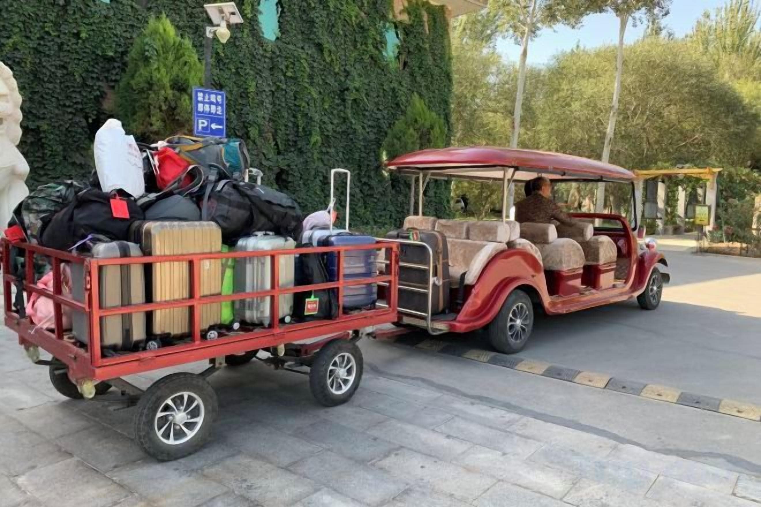 Un coche antiguo con equipaje sujeto en la parte trasera, estacionado en un área pavimentada.