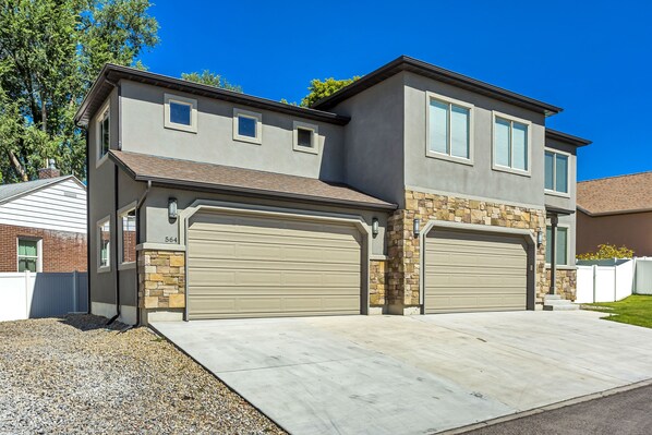 A two-story house with a garage, stone accents, and a clear driveway. - Spacious & New Guesthouse in Orem - Provo (Orem)