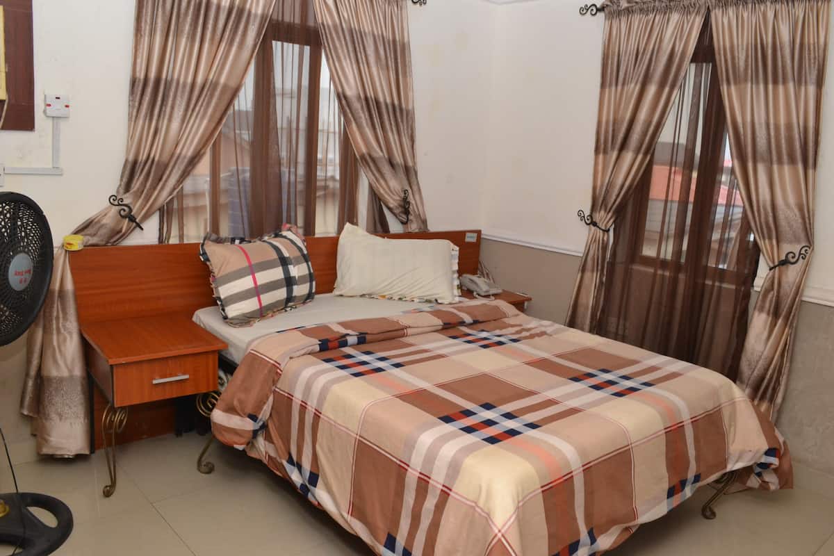A bedroom with a bed, bedside table, and curtains.