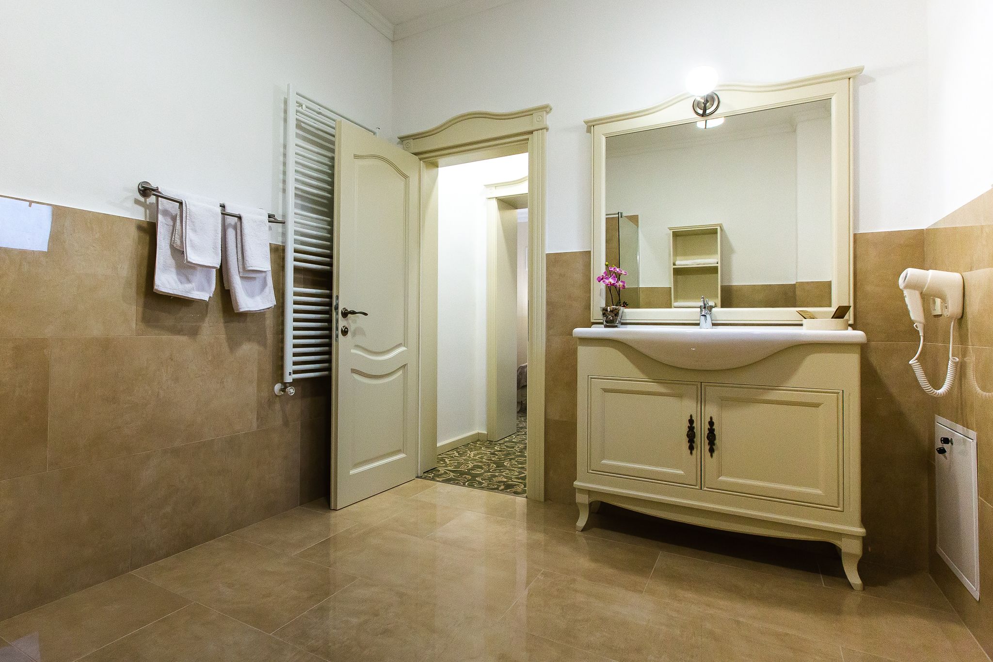 A bathroom with a beige vanity, a mirror, a towel rack, and a hairdryer.