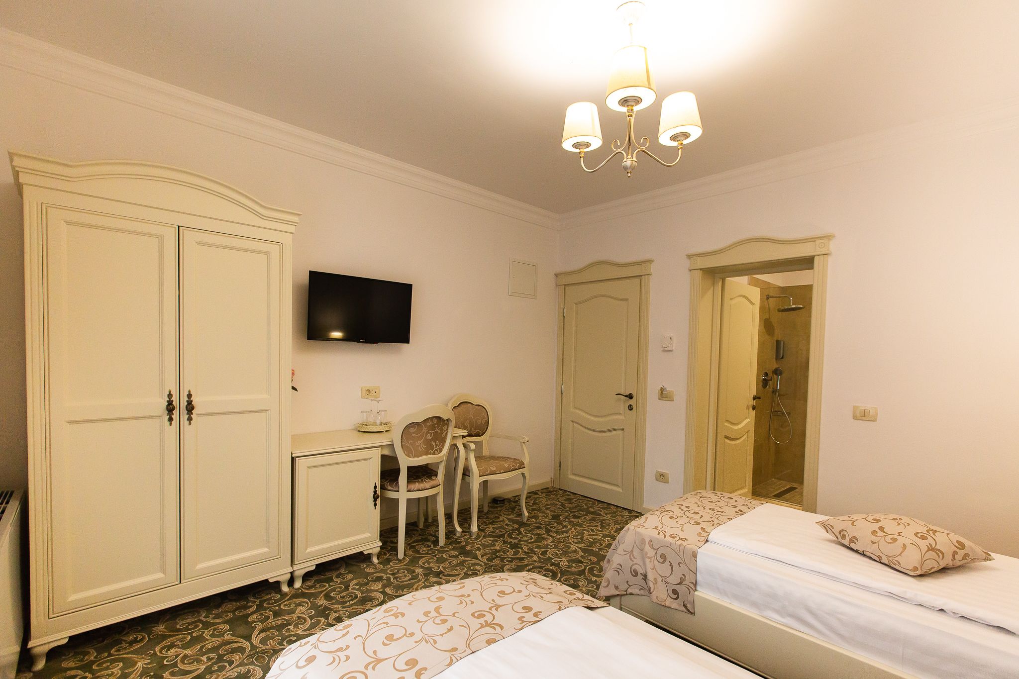 Habitación de hotel con dos camas, un escritorio, una silla, un televisor y un armario.