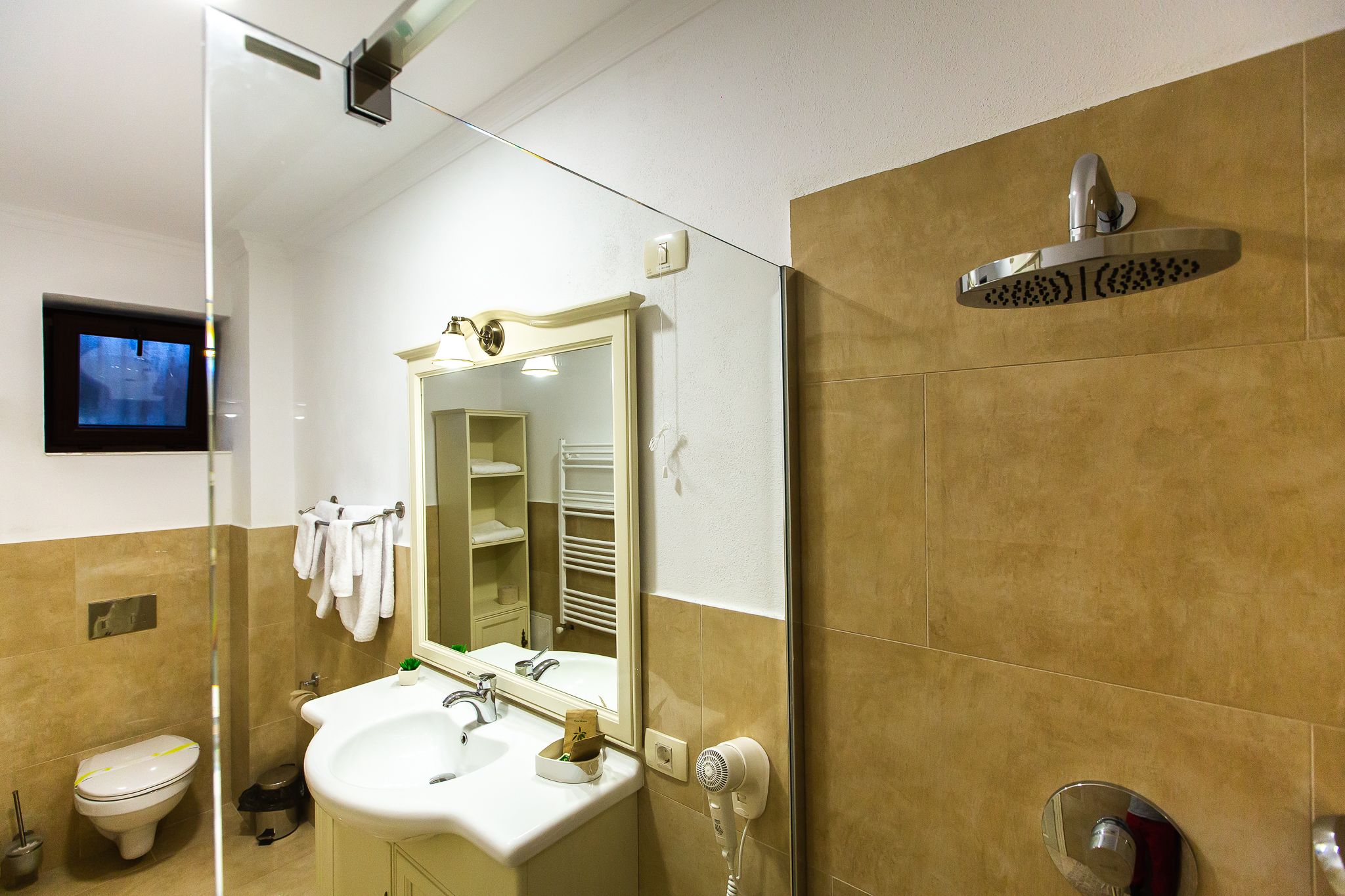 A bathroom with a toilet, sink, mirror, towel rack, and shower.