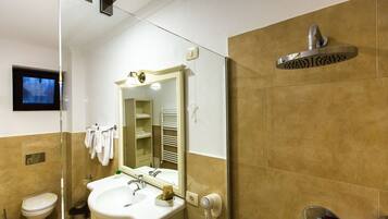 A bathroom with a toilet, sink, mirror, towel rack, and shower.