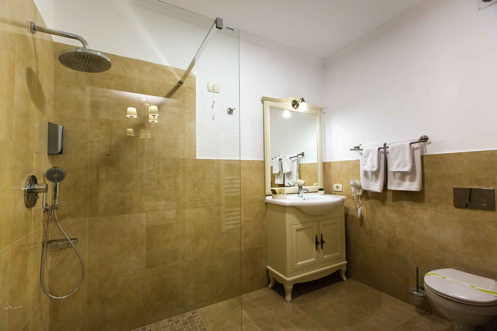 Une salle de bain avec une douche à parois de verre, un lavabo avec un miroir et des toilettes.