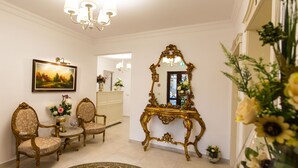 Una habitación con candelabro, espejo decorativo y arreglos florales.
