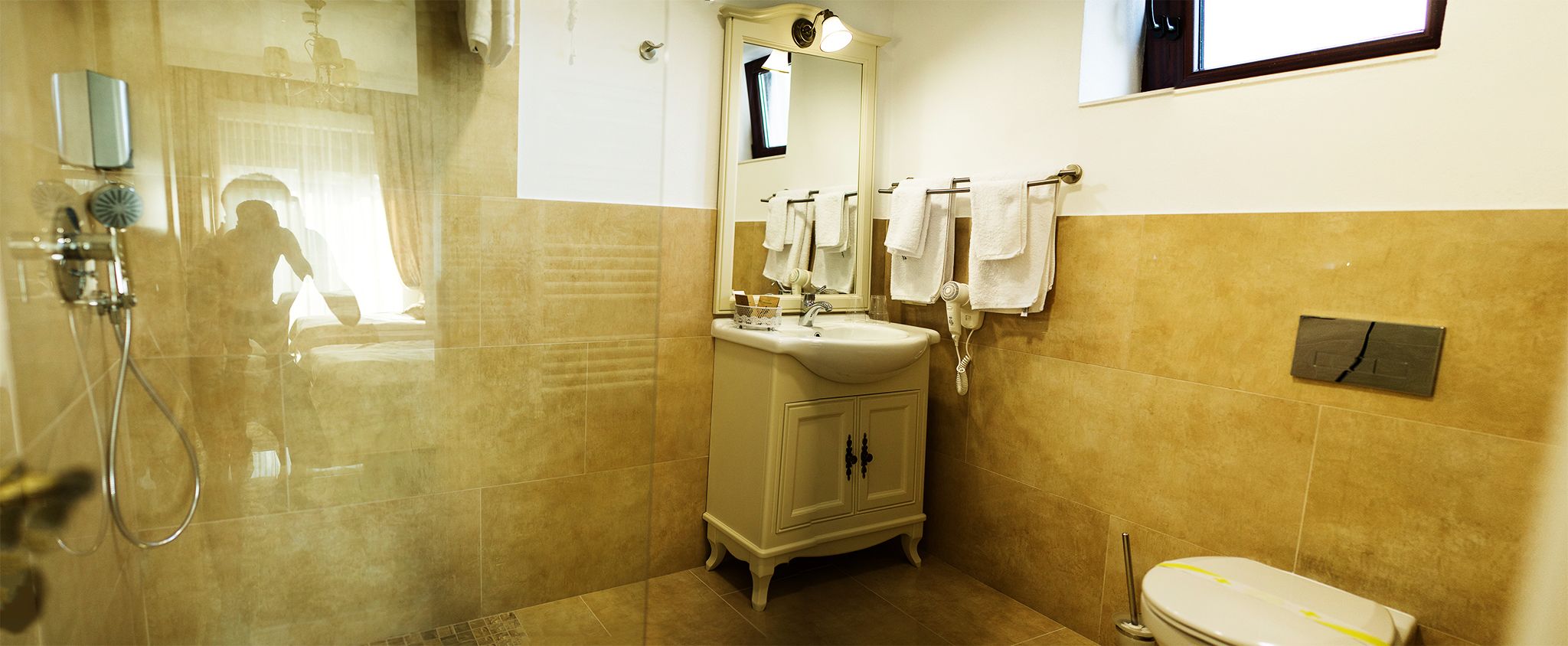 A bathroom with a glass shower enclosure, a sink with a mirror, and a toilet.