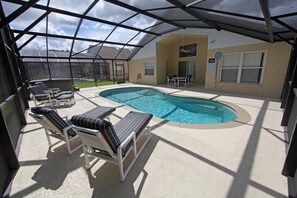 A covered outdoor swimming pool area with lounge chairs and a hot tub. - 4BR 3BA Home in Indian Creek by CV-2635 (Kissimmee)