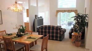 A dining area with a table set for four, a sofa, and a television in the background.