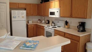 A kitchen with wooden cabinets, a refrigerator, a microwave, a stove, and a coffee maker.