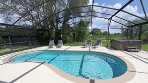 A covered swimming pool with lounge chairs and a hot tub.