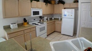 A kitchen with wooden cabinets, a microwave, stove, refrigerator, and a sink.
