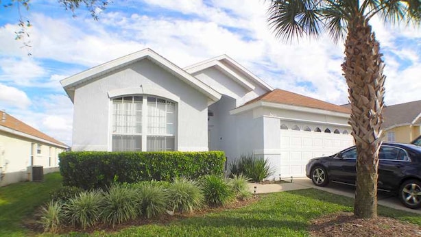A single-story house with a garage, a well-maintained lawn, and a palm tree.