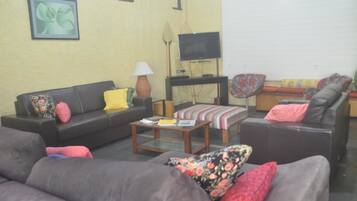 Uma sala de estar com sofá, mesa de centro, televisão e tapete estampado.