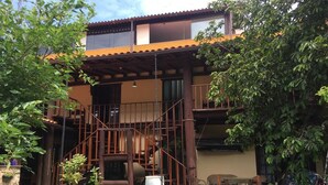 A two-story house with a wooden staircase, outdoor seating, and potted plants. - Hospedagem Praia de Piratininga (Niteroi)