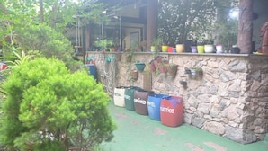 A stone wall with potted plants and a variety of colorful barrels labeled with different brands. - Hospedagem Praia de Piratininga (Niteroi)