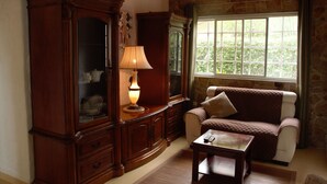 A cozy room with a wooden cabinet, a cushioned sofa, and a table with a lamp.