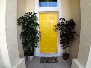 A yellow door with a doormat reading "WELCOME" in front. - 4BR 3BA Home in Windsor Palms by CV-8112 (Kissimmee)