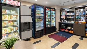 Eine Küchenzeile mit Kühlschrank, Mikrowelle, Kaffeemaschine und Getränkekühler.