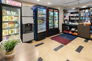 Uma área de cozinha compacta com geladeira, micro-ondas, cafeteira e refrigerador de bebidas.