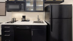 Une cuisine compacte équipée d’un four à micro-ondes, d’une machine à café, d’un évier, d’un lave-vaisselle et d’un réfrigérateur.