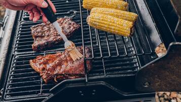 A grill with meat and corn on it.