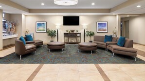 Eine geräumige Lobby mit einem großen Ecksofa, zwei Sessel, einem Couchtisch und einem an der Wand montierten Flachbildfernseher.