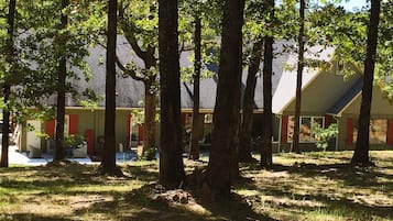 A building with a sloped roof, surrounded by trees and grass.