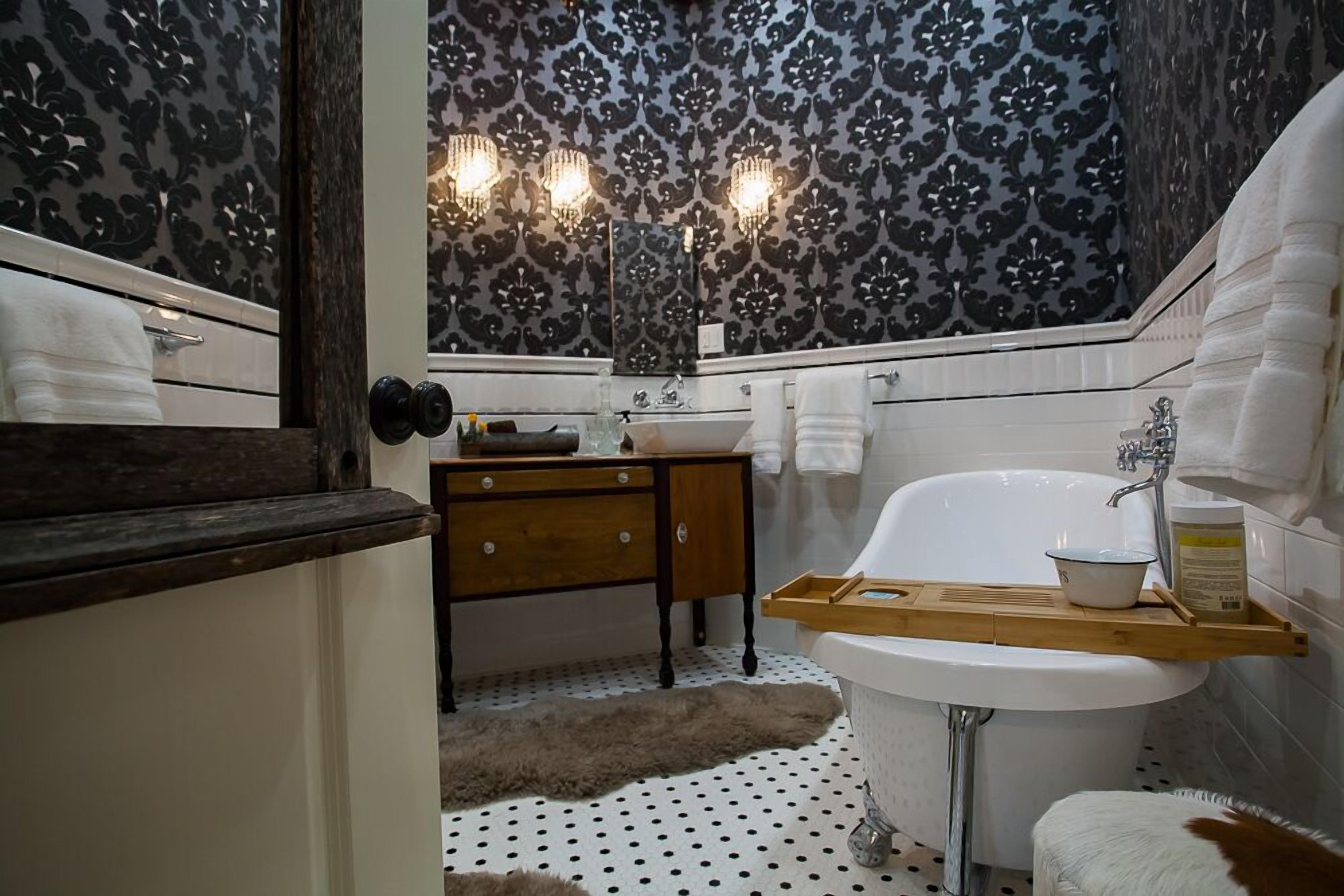 Un baño con bañera, tocador de madera y papel tapiz estampado.
