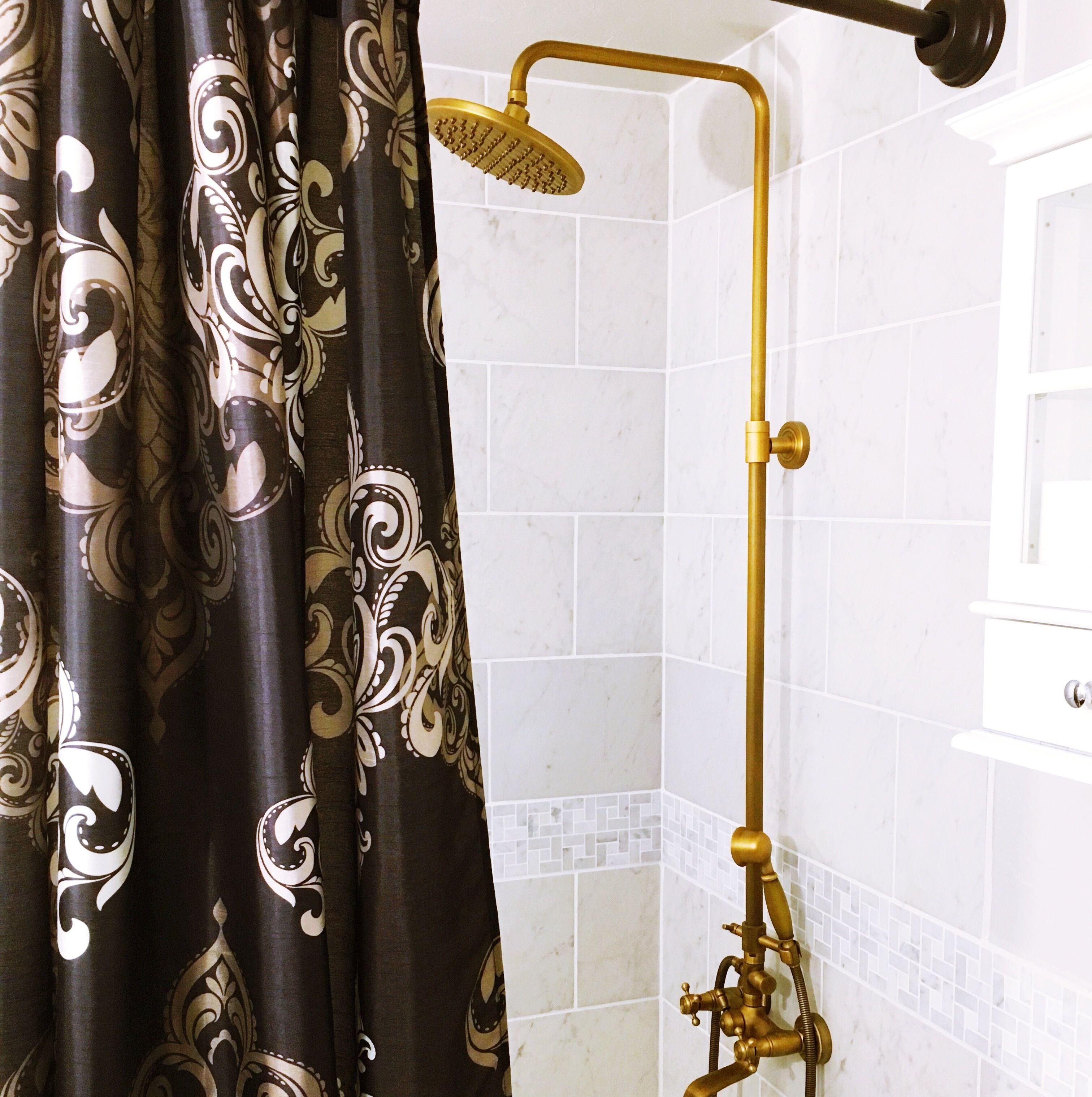 Een badkamer met een douche, witte betegelde muren en een decoratief gordijn.