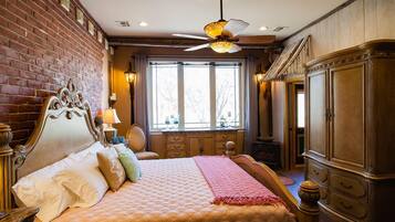 Une chambre avec un grand lit, une armoire en bois, un mur en briques et une fenêtre donnant sur un beau paysage.