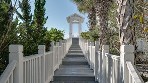 A wooden staircase leading to a white gazebo surrounded by lush greenery. - The Love Shack (Panama City Beach)