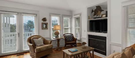 A living room with a fireplace, wicker furniture, and a television.