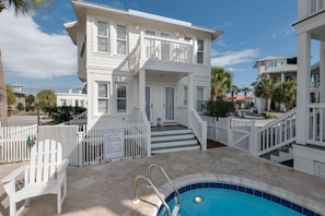 A white two-story building with a balcony, a swimming pool, and a white picket fence. - The Love Shack (Panama City Beach)