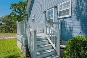 A blue house with a white front porch and steps leading to a door.