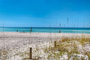 A sandy beach with a clear blue sky and calm sea. - Barefoot Beach Retreat 3 Bedroom Apartment (Panama City Beach)