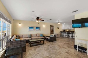 A spacious living area with a sofa set, a coffee table, and a dining area with bar stools. - Barefoot Beach Retreat 3 Bedroom Apartment (Panama City Beach)