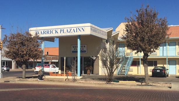 Un edificio con un letrero que dice "WARRICK PLAZA INN" y una escalera azul que lleva a la entrada.