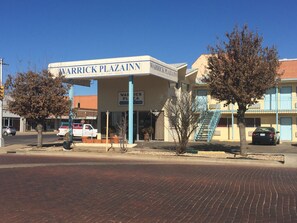 Un edificio con un letrero que dice "WARRICK PLAZA INN" y una escalera azul que lleva a la entrada.