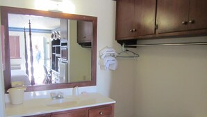 Un baño con tocador de madera, un espejo, un lavabo y un perchero para toallas.